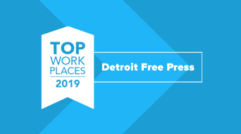Blue image featuring a white ribbon with TOP WORK PLACES 2019 text on the left. To the right, it reads Detroit Free Press in a white-bordered box. Diagonal geometric shapes form the background.