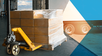 A stack of cardboard boxes wrapped in plastic rests on a pallet jack at a small-business-shipping-hub. Positioned by the loading dock, the open door reveals the back of a truck parked outside, with sunlight streaming in.