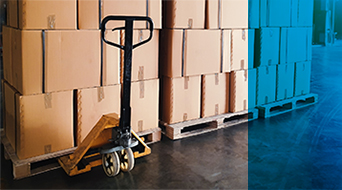A yellow hand pallet truck is poised before towering stacks of brown cardboard boxes on wooden pallets in a bustling small-business shipping hub. The concrete floor adds an industrial touch, while a blue overlay graces the right side of the image.