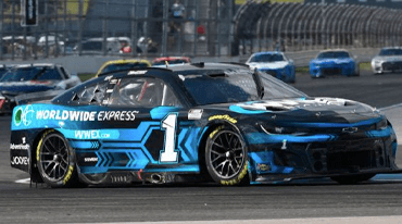 A racing car with the number 1 on the side, featuring a blue and black design and Worldwide Express branding, speeds on a track with several other cars in the background.
