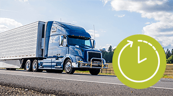 A blue semi-truck drives on a highway under a partly cloudy sky. In the foreground, theres a green clock icon with an arrow indicating rotation. Fields and trees are visible in the background.