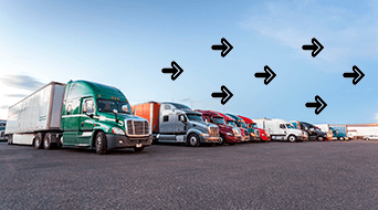 A row of parked semi-trucks in various colors, including green, red, and white, are lined up in a large parking lot under a blue sky. Black arrows are drawn above, pointing to the right.