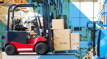 A red forklift is efficiently maneuvering a stack of cardboard boxes, ready for large package shipping, across a brightly lit warehouse. Shelves filled with boxes and various equipment are visible in the background.
