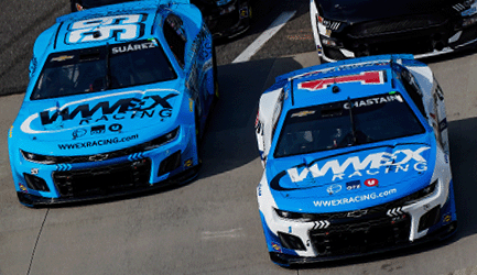 Two blue NASCAR race cars with white hoods and prominent WWEX Racing logos thunder around the track. Each car carries a unique number on its windshield, while other racers in black and gray linger in the background, adding to the thrilling atmosphere.