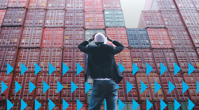 A person wearing a hard hat stands with their back to the camera, looking at a large stack of colorful shipping containers. Blue arrows are overlaid across the bottom of the image, pointing to the right.