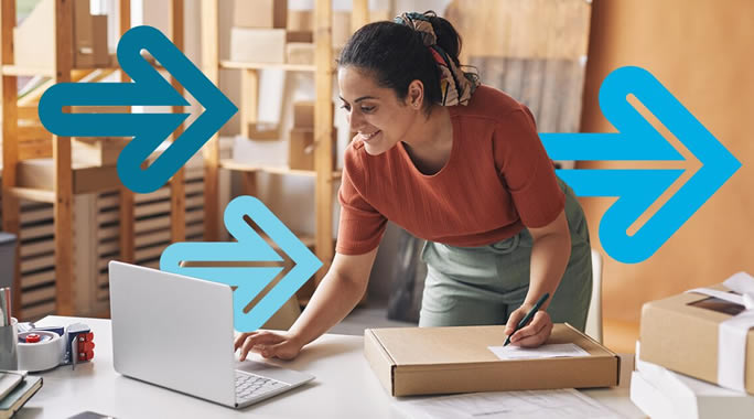 A woman in an orange shirt leans over a table, using a laptop and writing on a package. Blue arrows are superimposed, pointing to the right. The background shows shelves with items.