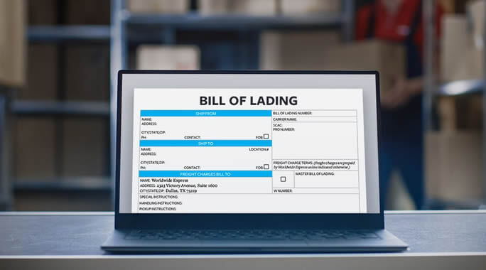 A laptop screen displays a digital bill of lading form in a warehouse, with shelves and a person blurred in the background.